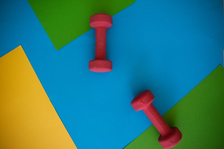 Hanteln auf farbigem Hintergrund als Symbol für Krafttraining und geistige Leistungsfähigkeit